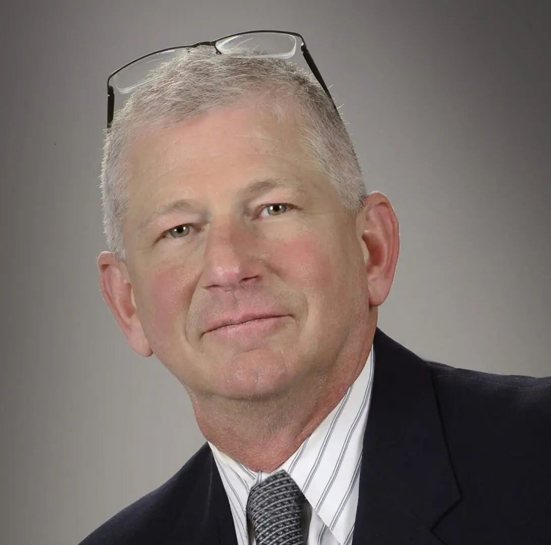 Man wearing suit with glasses on head.