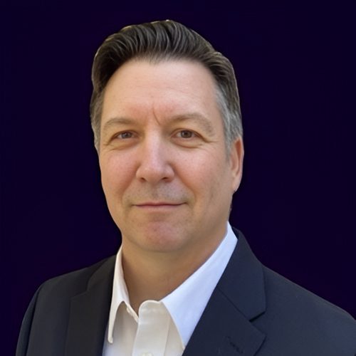 A man in a suit and tie standing next to a wall.
